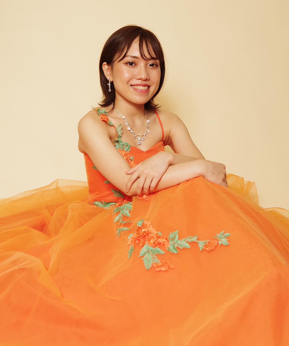 暖かみのあるオレンジカラーのドレスを着用した笑顔あふれる演奏会用宣材写真