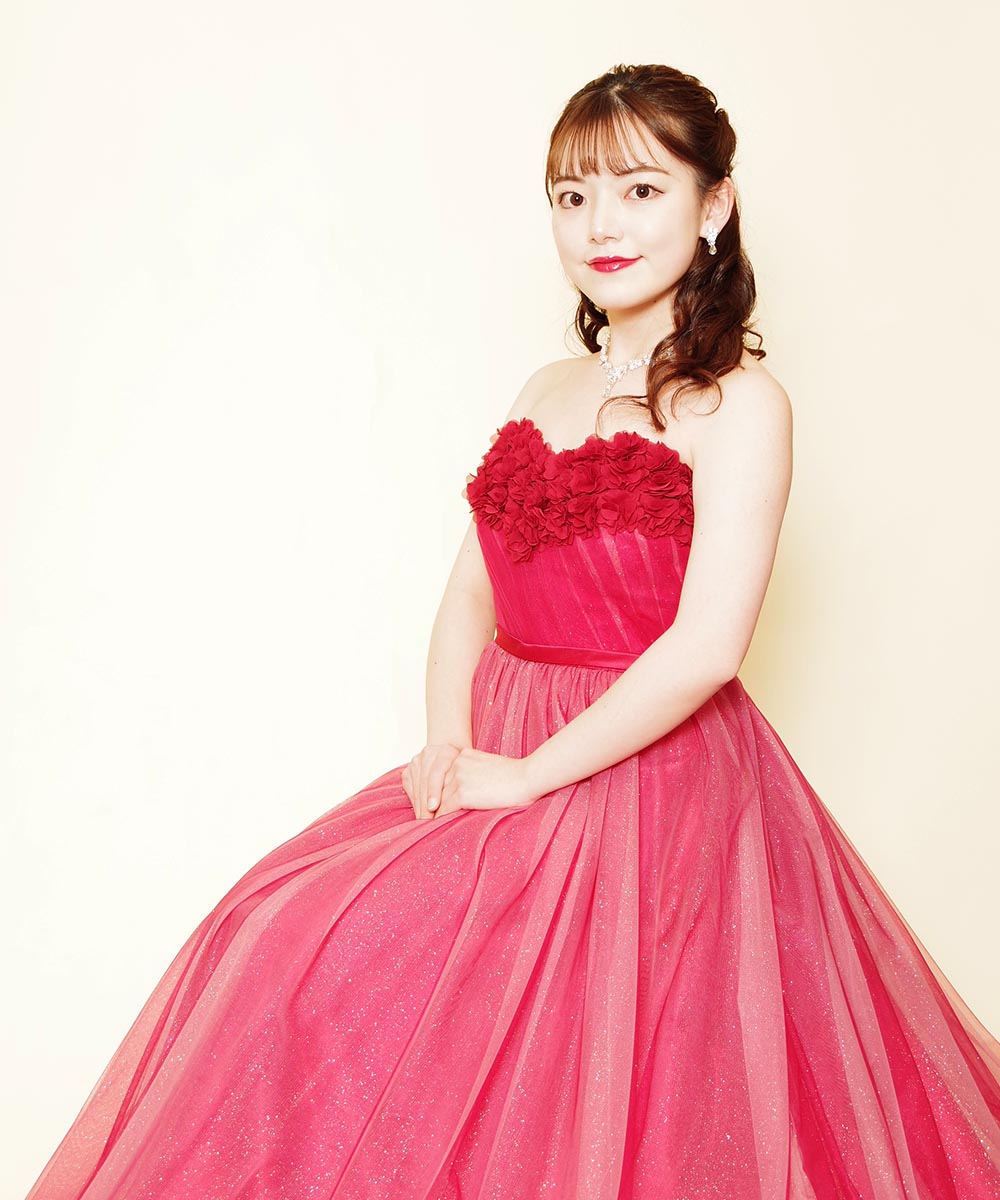 胸元立体バラデザインのレッドカラードレスを着用したピアニストのお客様の宣材写真